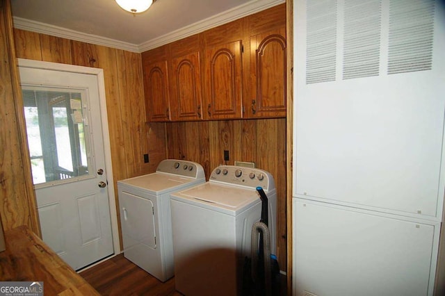 laundry area with dark wood finished floors, cabinet space, wood walls, crown molding, and washing machine and clothes dryer