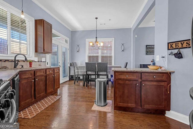 kitchen with hanging light fixtures, dark wood-type flooring, a notable chandelier, and crown molding