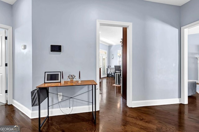 hallway featuring dark wood finished floors and baseboards