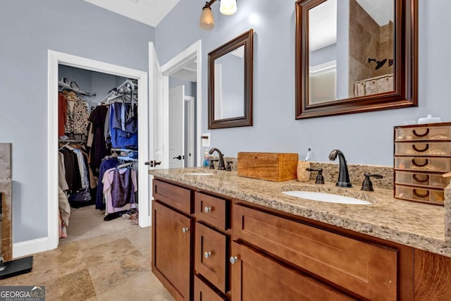 bathroom featuring double vanity, a walk in closet, and a sink