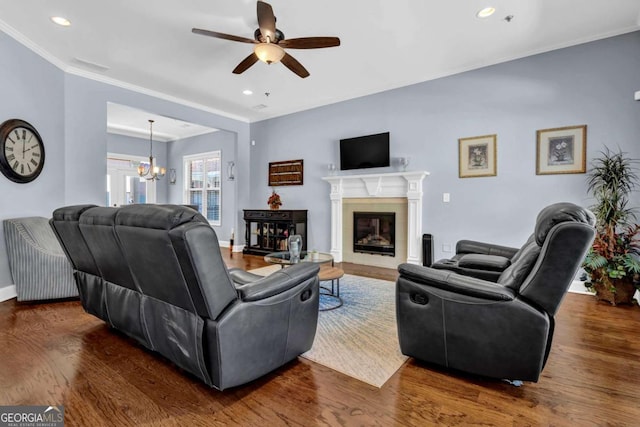 living room featuring ornamental molding, ceiling fan with notable chandelier, recessed lighting, baseboards, and dark wood-style flooring