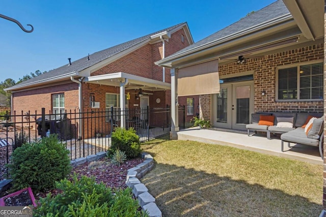 rear view of property with fence, french doors, a yard, brick siding, and a patio area