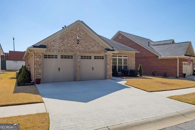 view of front of property with brick siding, a front lawn, an attached garage, and driveway