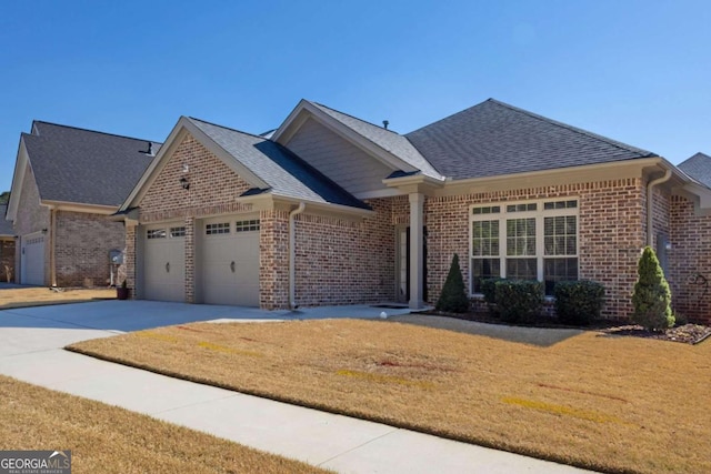 view of front facade with a front yard, driveway, a shingled roof, a garage, and brick siding