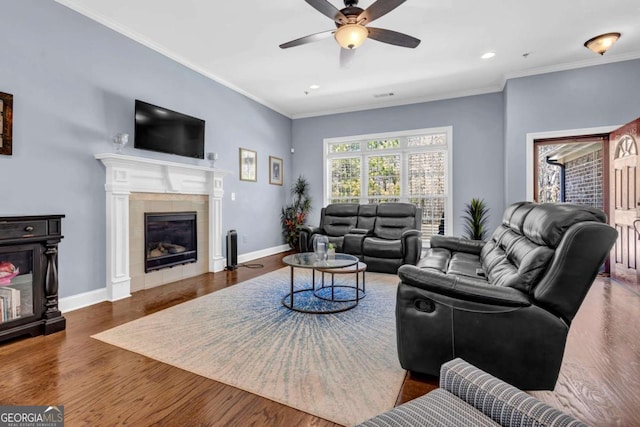 living area with crown molding, wood finished floors, and ceiling fan