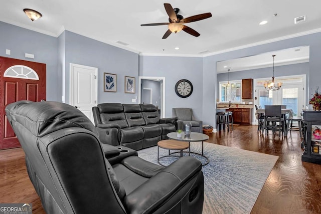 living room with dark wood-style floors, visible vents, ceiling fan with notable chandelier, and crown molding