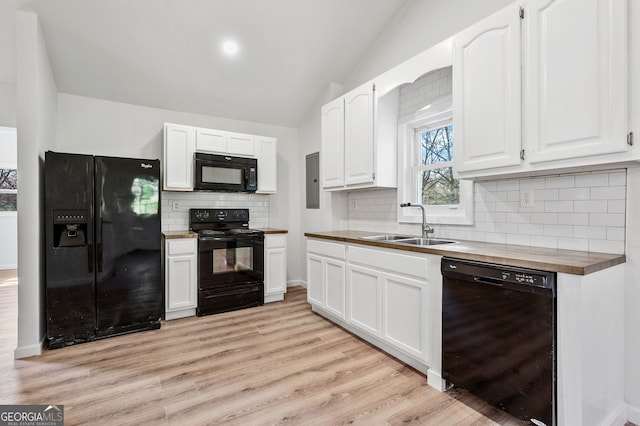 kitchen featuring a sink, lofted ceiling, black appliances, and white cabinetry