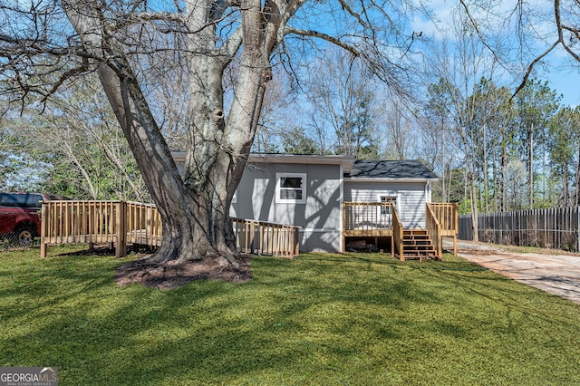 exterior space with a wooden deck, a lawn, and fence