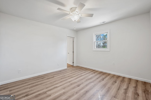 spare room featuring a ceiling fan, light wood-style flooring, baseboards, and visible vents