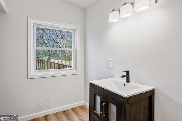 bathroom with wood finished floors, baseboards, and a sink