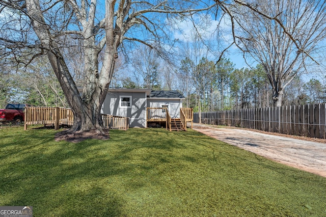 view of yard featuring a deck, driveway, and fence