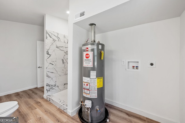 utility room with visible vents and water heater