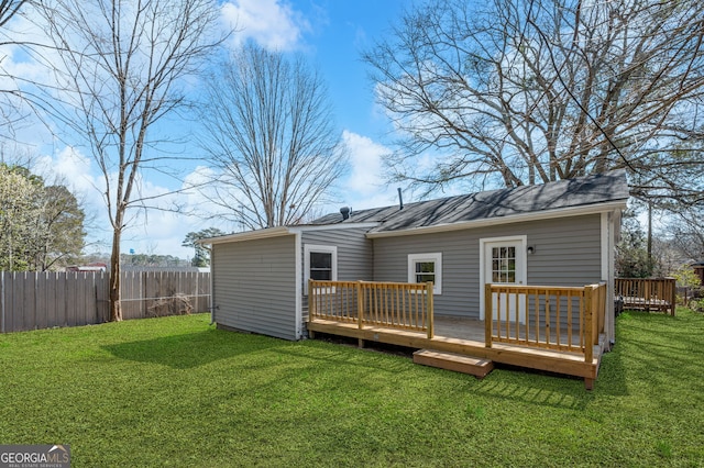 back of property featuring a yard, a wooden deck, and fence