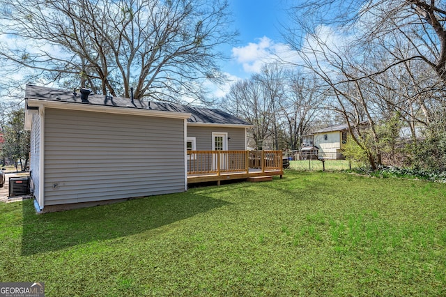 rear view of house with a deck, a lawn, and fence