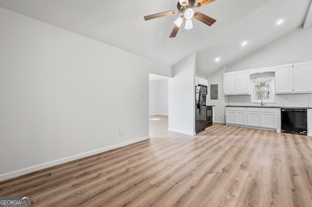 unfurnished living room featuring a ceiling fan, lofted ceiling, light wood-style flooring, electric panel, and a sink