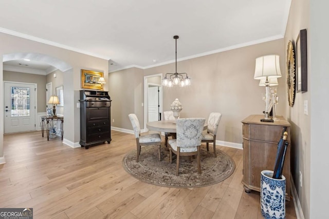 dining space with baseboards, arched walkways, ornamental molding, and light wood finished floors