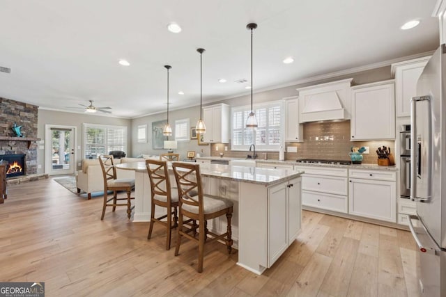 kitchen featuring ornamental molding, a sink, open floor plan, stainless steel appliances, and custom exhaust hood