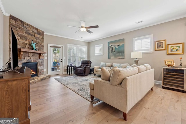 living area featuring visible vents, ornamental molding, ceiling fan, wine cooler, and light wood-type flooring