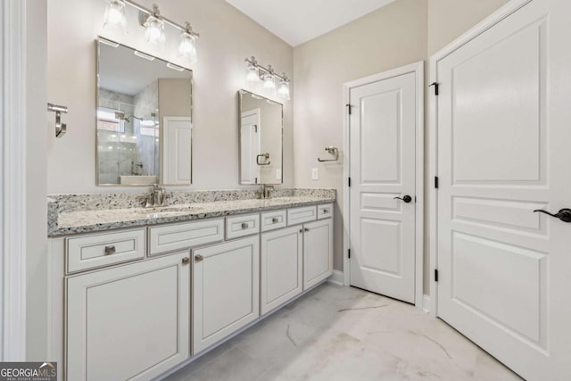 full bath featuring a sink, double vanity, marble finish floor, and a stall shower