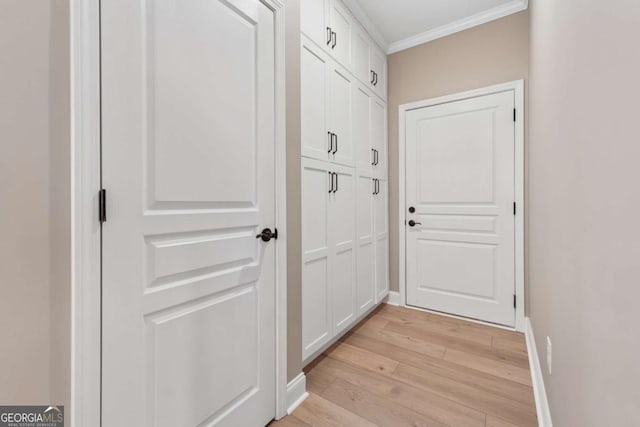 doorway to outside featuring baseboards, light wood-style flooring, and crown molding