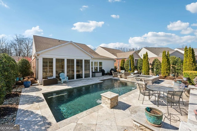 pool with an in ground hot tub, a fire pit, a sunroom, and a patio