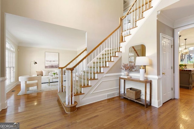 stairway with crown molding and wood finished floors