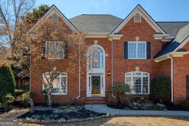 traditional home with brick siding and roof with shingles