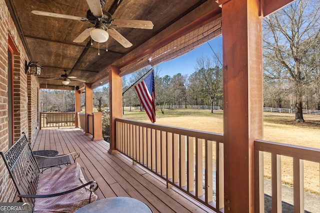 wooden terrace featuring a porch, a ceiling fan, and fence