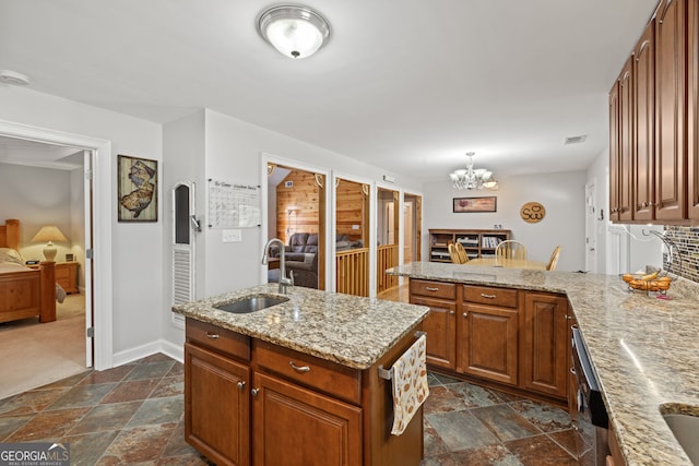 kitchen with visible vents, a peninsula, a sink, stone finish floor, and a notable chandelier