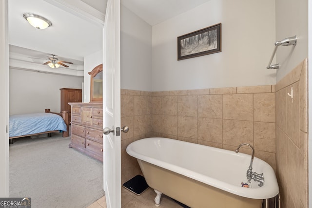 ensuite bathroom featuring ensuite bath, ceiling fan, tile patterned flooring, a freestanding bath, and tile walls