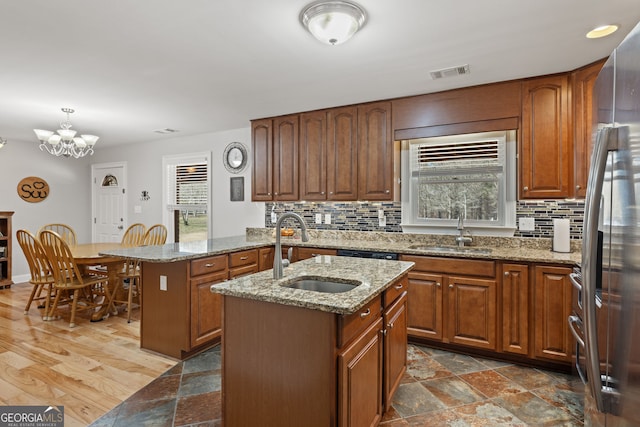 kitchen featuring an inviting chandelier, an island with sink, visible vents, and a sink