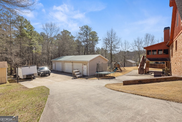 exterior space with a detached garage, an outdoor structure, a playground, and a trampoline