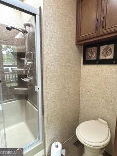 bathroom featuring toilet and a stall shower