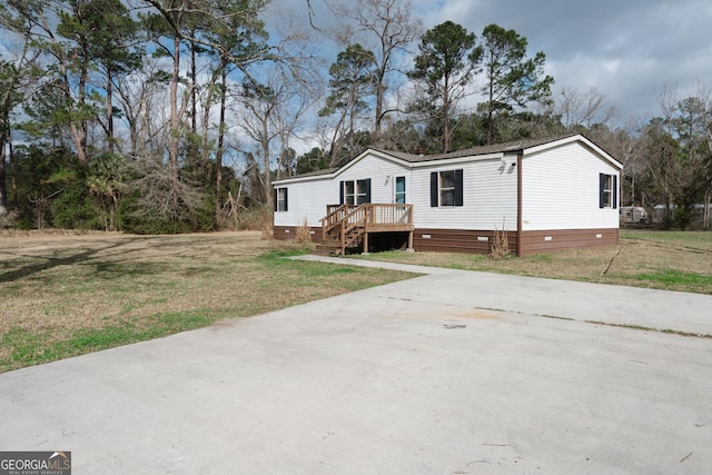 manufactured / mobile home with crawl space, concrete driveway, a wooden deck, and a front lawn