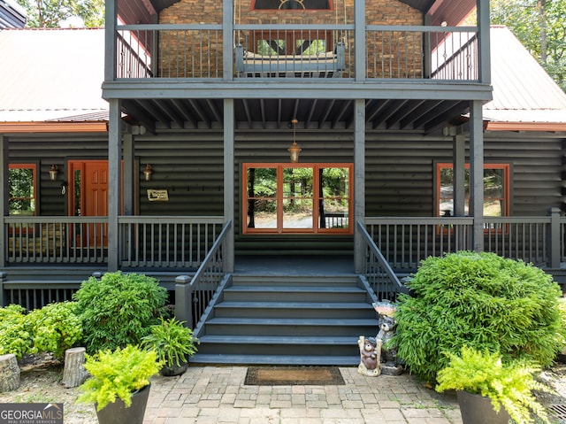 property entrance with a porch, a balcony, and metal roof