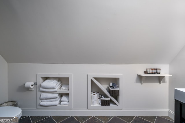 bathroom with toilet, baseboards, vanity, and lofted ceiling