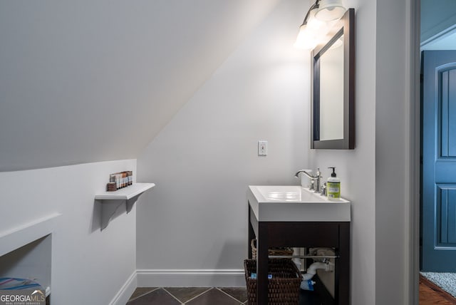 bathroom with tile patterned floors, baseboards, lofted ceiling, and vanity