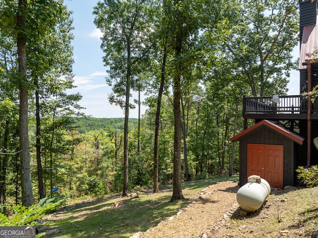 view of yard featuring a view of trees and a deck