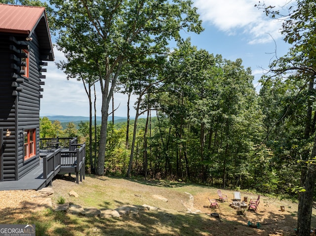 view of yard featuring a deck and an outdoor fire pit