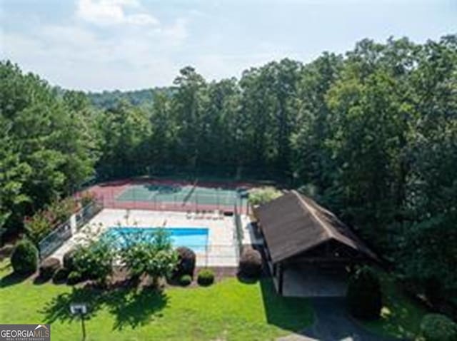 view of pool with a yard and a view of trees