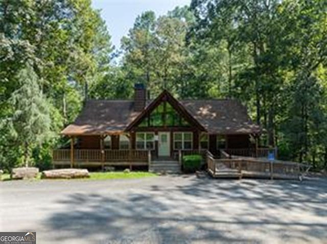 chalet / cabin featuring a chimney and gravel driveway