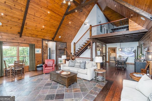 living area featuring stairway, wooden walls, high vaulted ceiling, beam ceiling, and wood ceiling