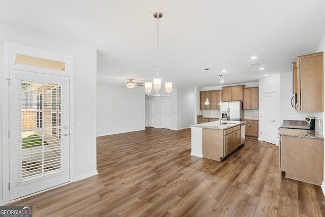 kitchen featuring an island with sink, a sink, dark wood-type flooring, fridge with ice dispenser, and a chandelier