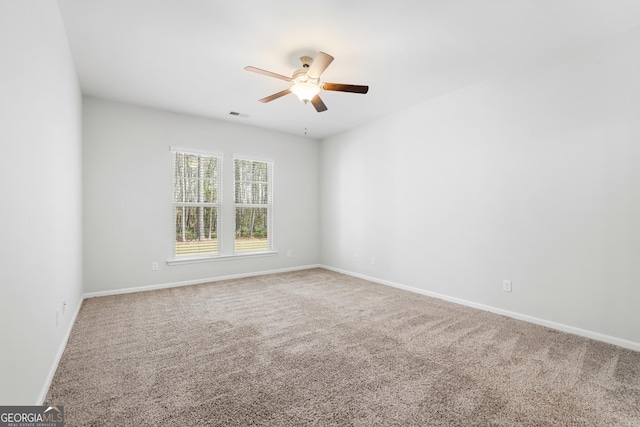 carpeted spare room with visible vents, baseboards, and a ceiling fan