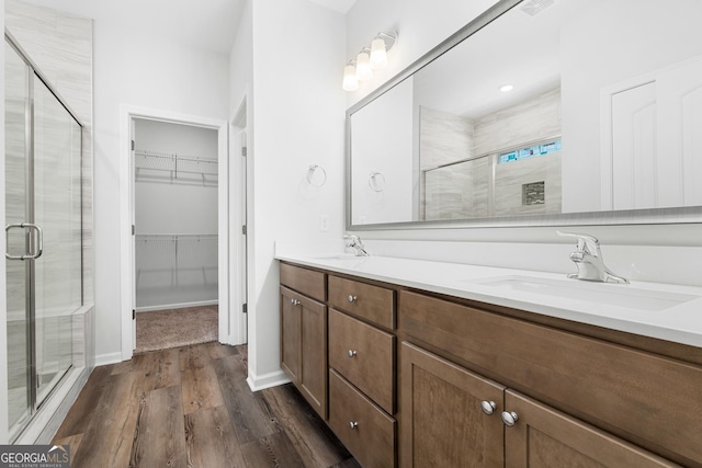 full bath featuring double vanity, a stall shower, and a sink