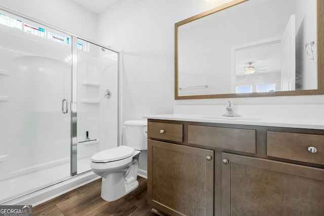 full bath featuring toilet, wood finished floors, a shower stall, ceiling fan, and vanity