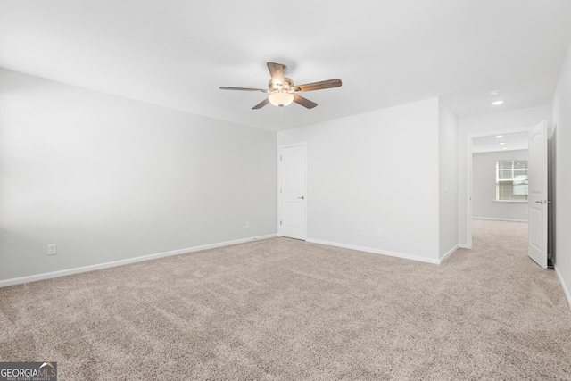 spare room featuring light carpet, baseboards, and ceiling fan