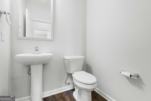 bathroom featuring toilet, baseboards, and wood finished floors