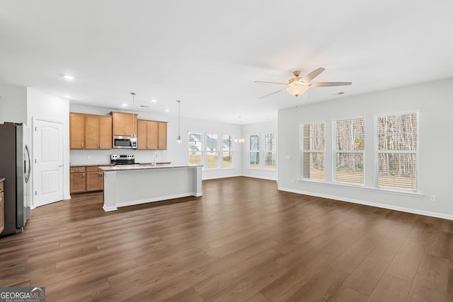 kitchen with an island with sink, open floor plan, appliances with stainless steel finishes, ceiling fan, and dark wood-style flooring