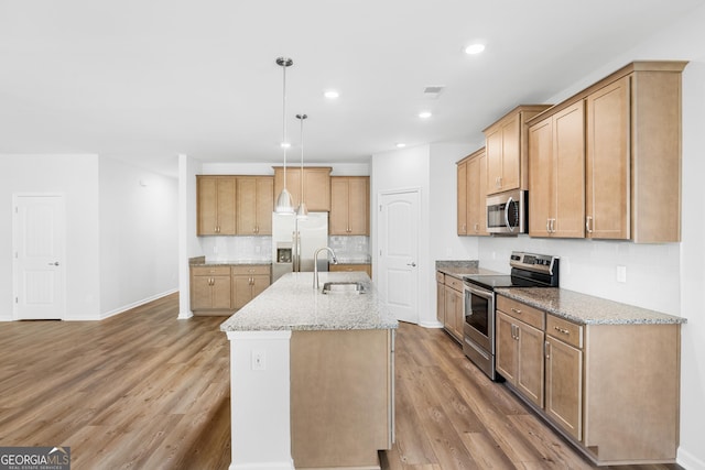 kitchen featuring visible vents, light wood-type flooring, light stone counters, appliances with stainless steel finishes, and a sink